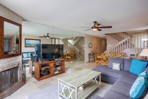 A living room with a TV, sofa, coffee table, and fireplace.
