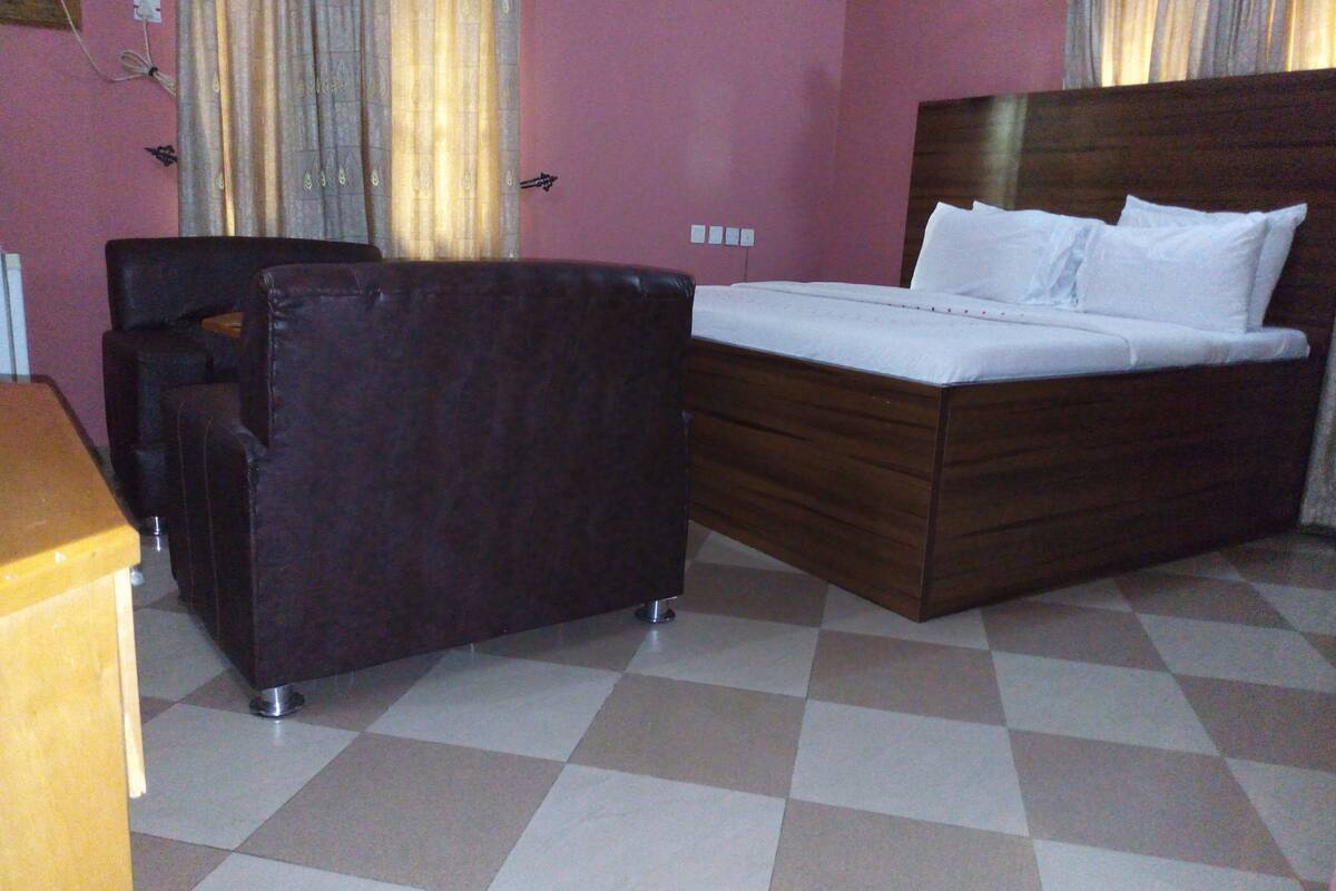 Ein Hotelzimmer mit einem Bett, einem Sessel, einem Schreibtisch und einem karierten Boden.