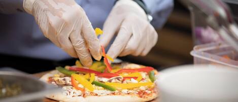 A person preparing a pizza with various toppings.