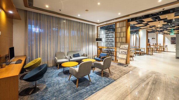 A modern hotel lobby with a reception desk, seating area, and a dining space. - Holiday Inn Express Chennai OMR Thoraipakkam by IHG (Chennai)