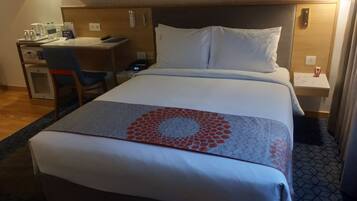 Une chambre d’hôtel avec un lit, un bureau, une chaise et une petite table.