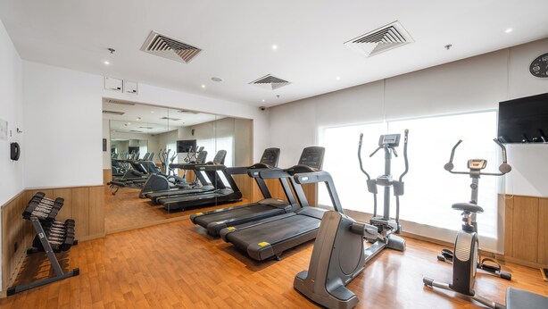 Un gimnasio con cintas de correr, elípticas y pesas sueltas.