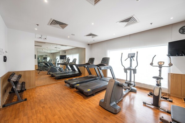 Un gimnasio con cintas de correr, elípticas y pesas sueltas.