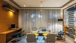 A modern hotel room with a wooden desk, two armchairs, a sofa, and a decorative wall with vases. - Holiday Inn Express Chennai OMR Thoraipakkam by IHG (Chennai)