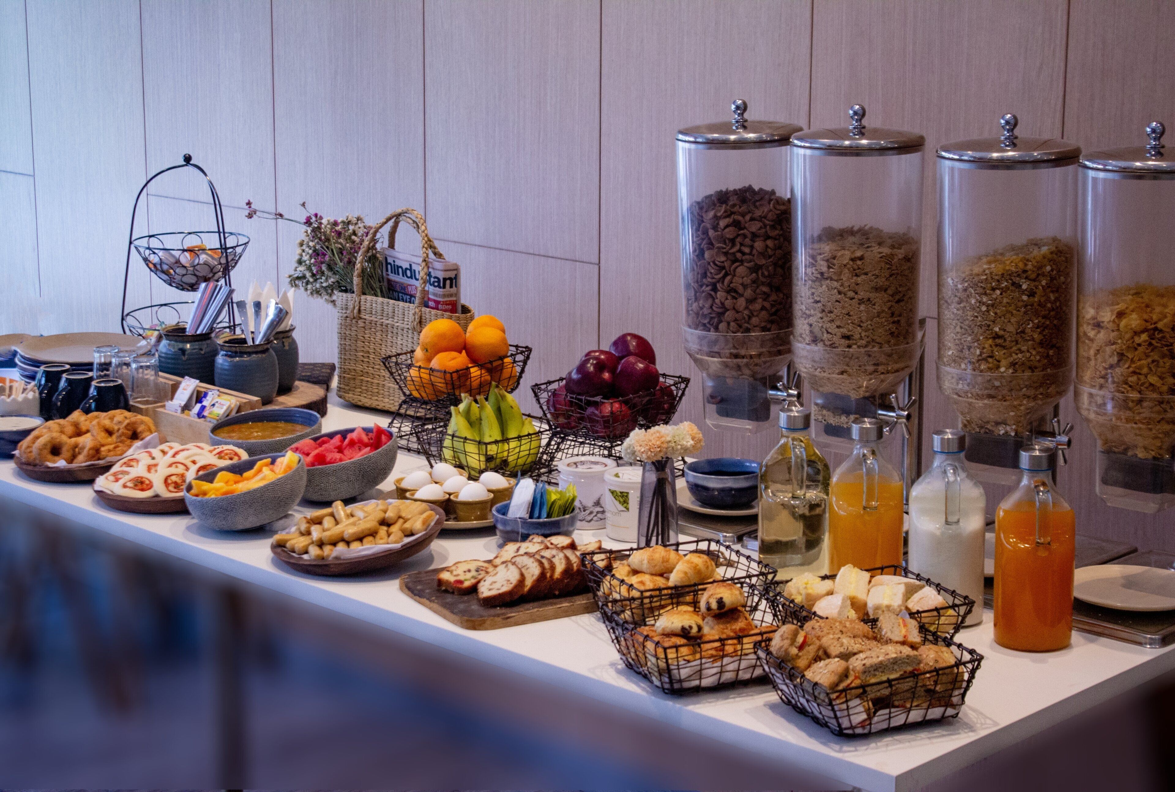 A buffet with various food items, including fruits, cereals, and pastries.