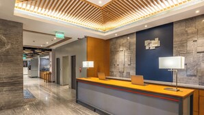 A modern reception desk with two laptops, a wall-mounted clock, and a reception area with a wooden accent wall and a blue accent wall. - Holiday Inn Express Chennai OMR Thoraipakkam by IHG (Chennai)