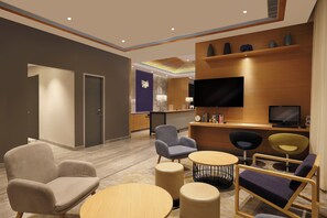 Un hall d’hôtel moderne comprenant un comptoir d’accueil, un espace salon et un grand téléviseur à écran plat.