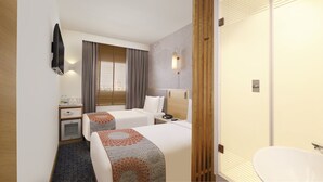 Habitación de hotel con dos camas, un escritorio, un minibar, un televisor y un baño.