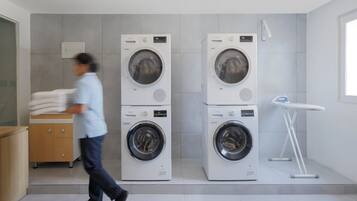 Une buanderie équipée de deux machines à laver superposées et d’un sèche-linge.
