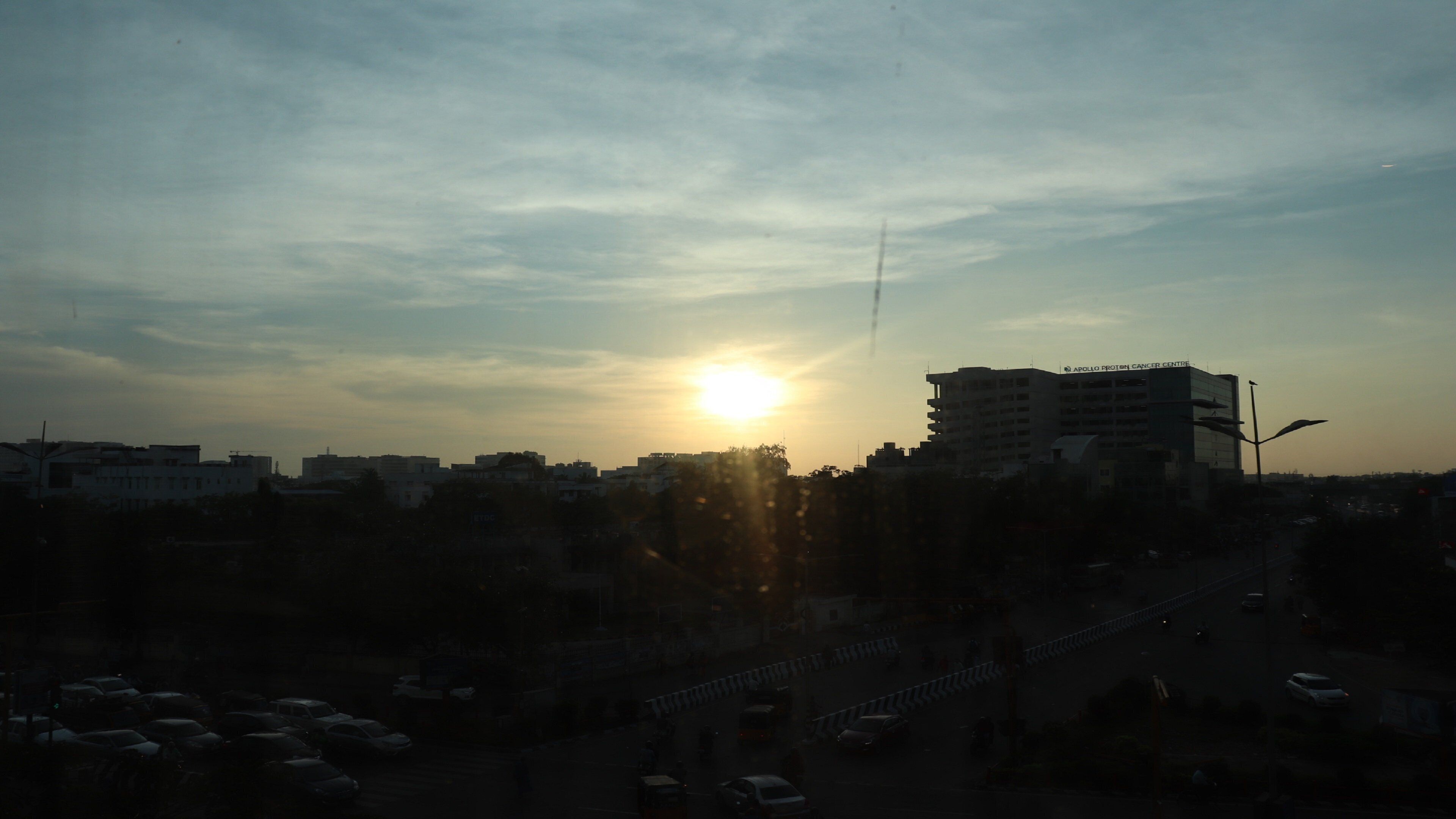 A cityscape with buildings and a road during sunset.