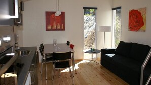 A modern kitchen with a dining table and chairs, a black sofa, and a large window.