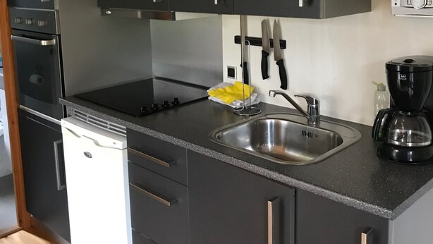 A modern kitchen with black cabinets, stainless steel appliances, and a black countertop.