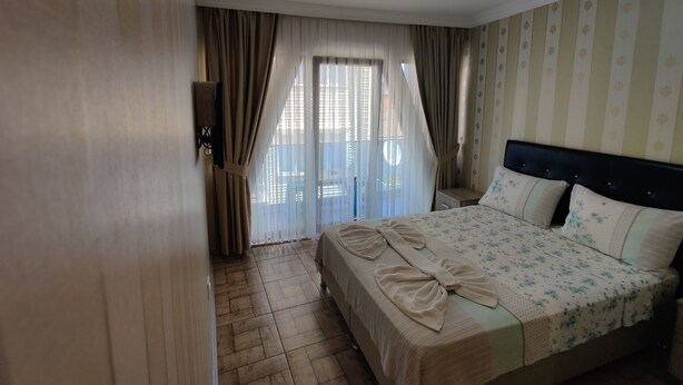 Habitación de hotel con cama, cortinas, ventana y una lámpara en el techo.