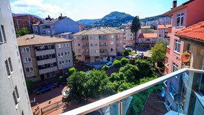 Un edificio de varios pisos con balcones, vista a la calle y un paisaje montañoso al fondo.