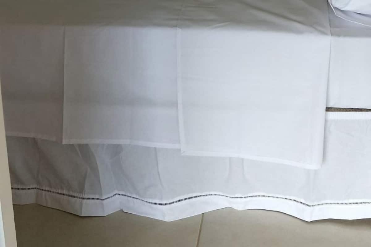 Uma cama beliche com um edredom verde e roupa de cama branca.