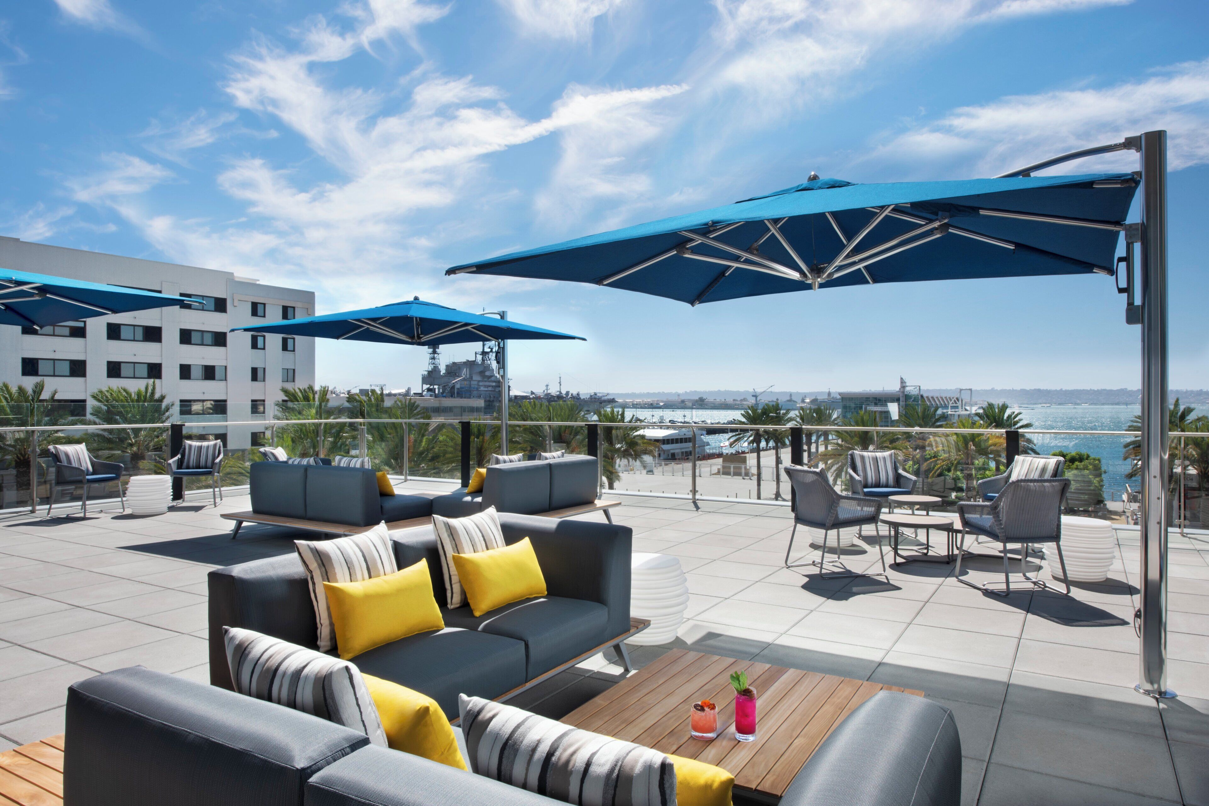 A rooftop terrace with outdoor seating, umbrellas, and a view of the sea.