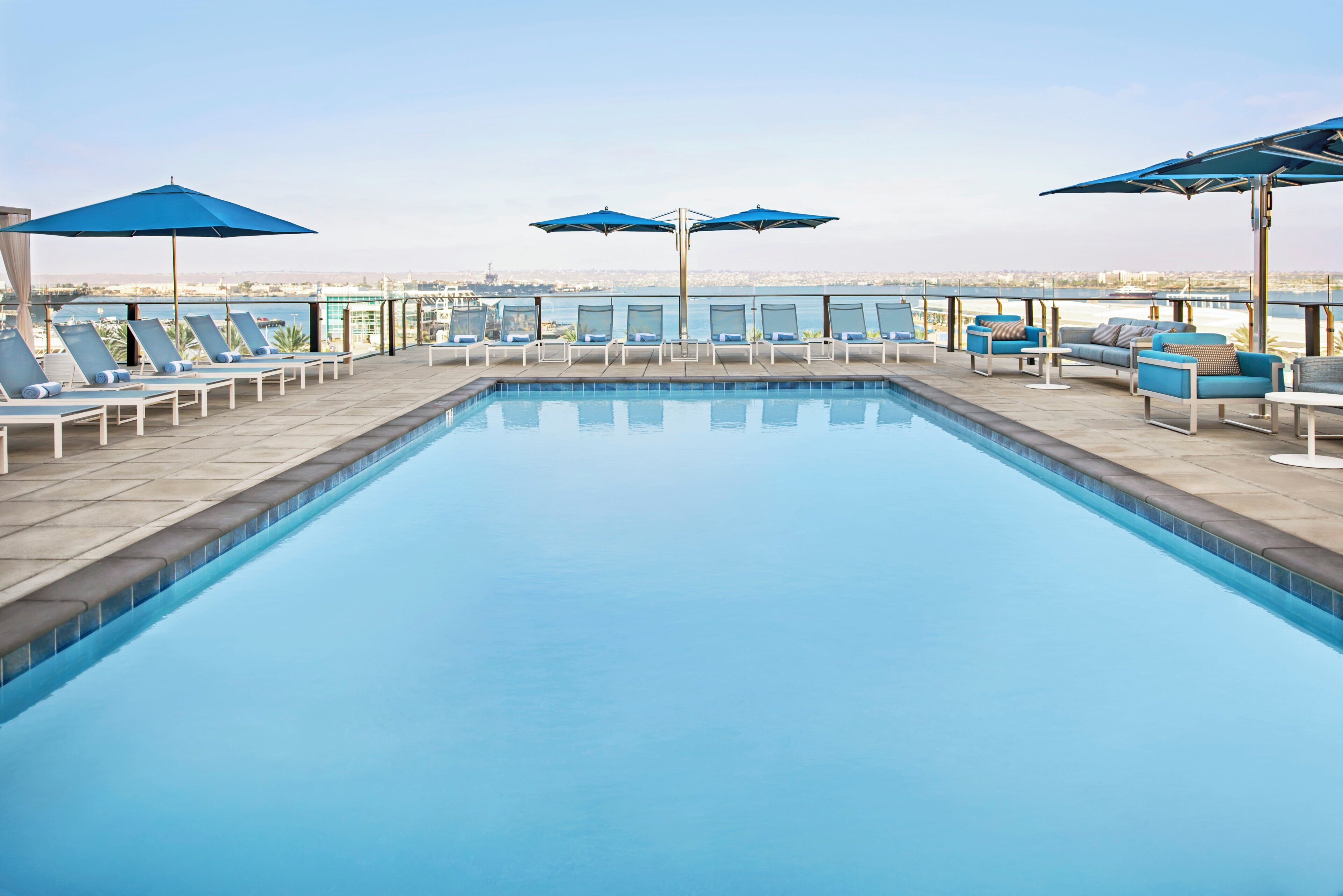 Une piscine entourée de chaises longues et de parasols, avec une vue imprenable sur le paysage urbain.