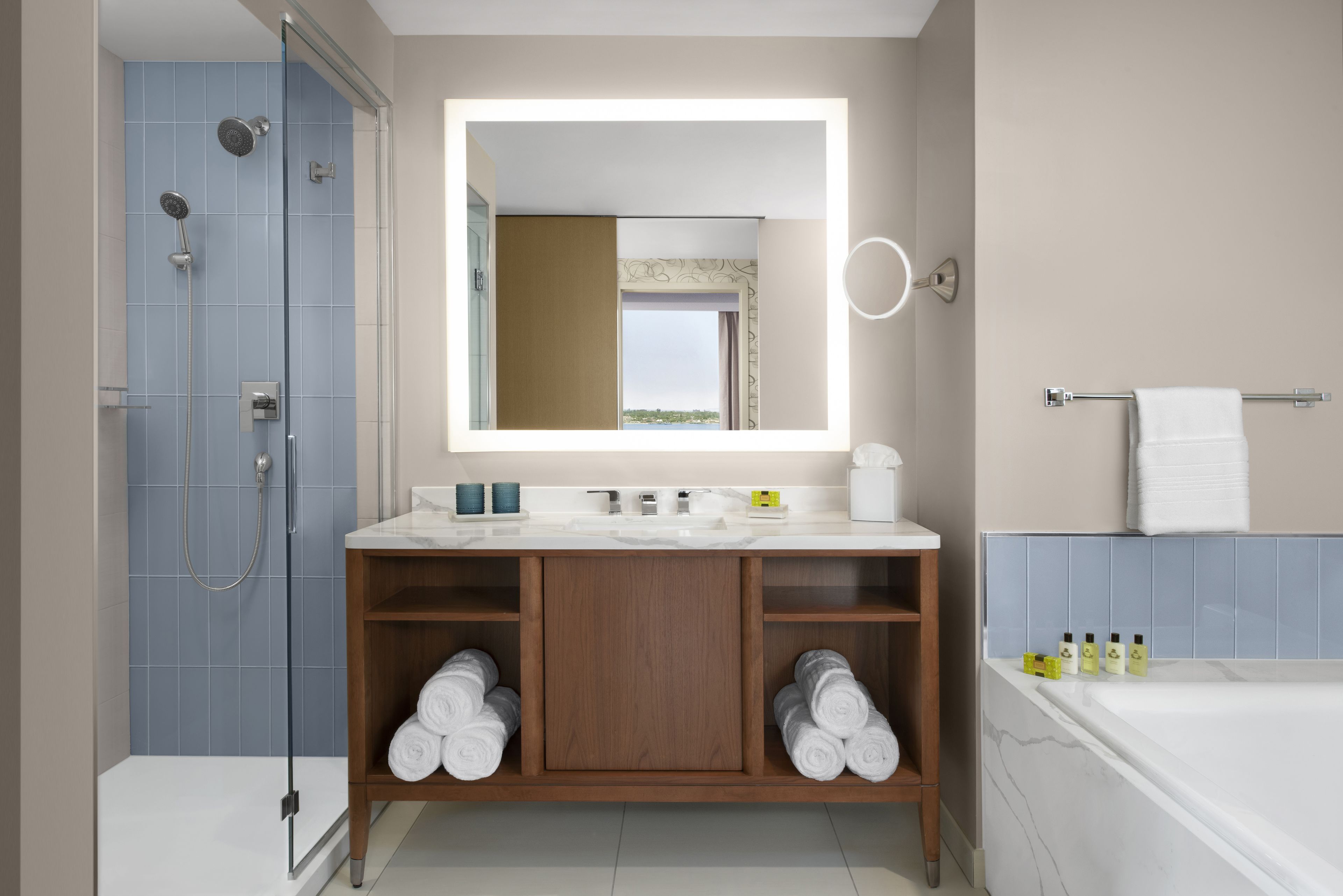 Une salle de bain moderne avec une douche à l’italienne en verre, un meuble-lavabo en bois avec un miroir et une baignoire.