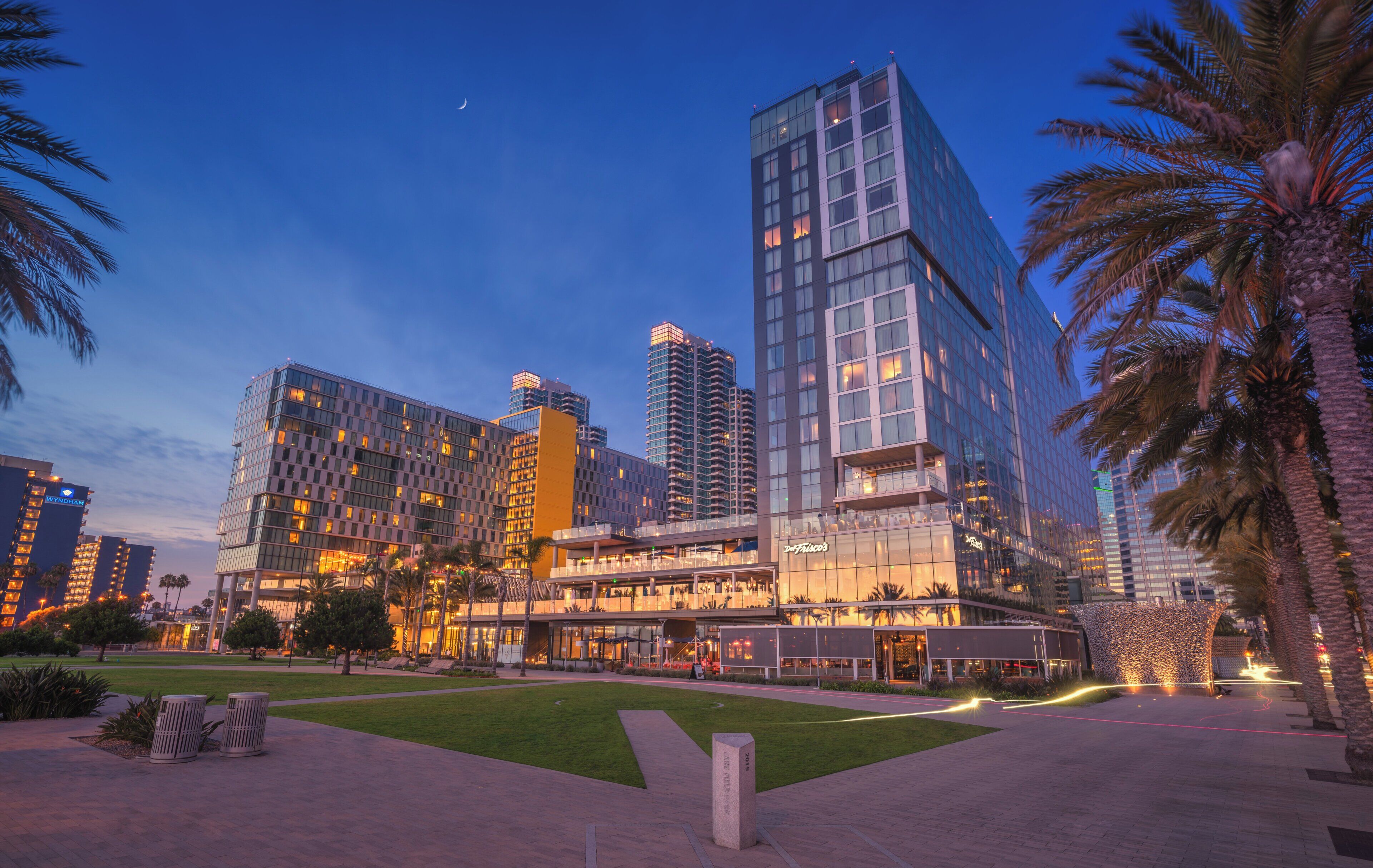 A modern hotel with multiple floors, a central atrium, and a landscaped courtyard with palm trees.