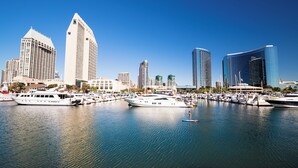 A marina with several yachts docked, surrounded by modern high-rise buildings.