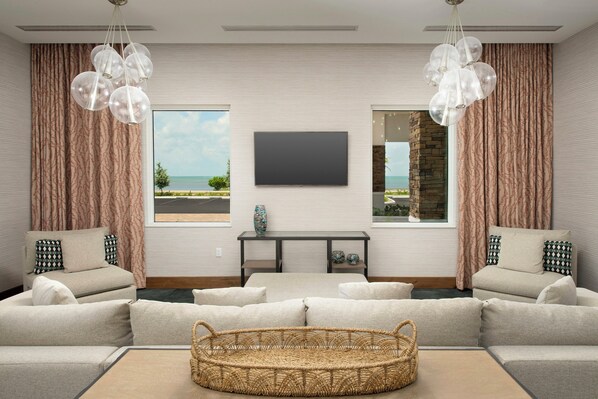 Una sala de estar con un sofá grande, un televisor, una mesa de centro y vistas al mar.