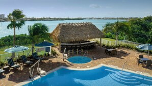 A pool area with lounge chairs, a thatched-roof structure, and a view of the water. - Hampton Inn Marathon - Florida Keys (Marathon)