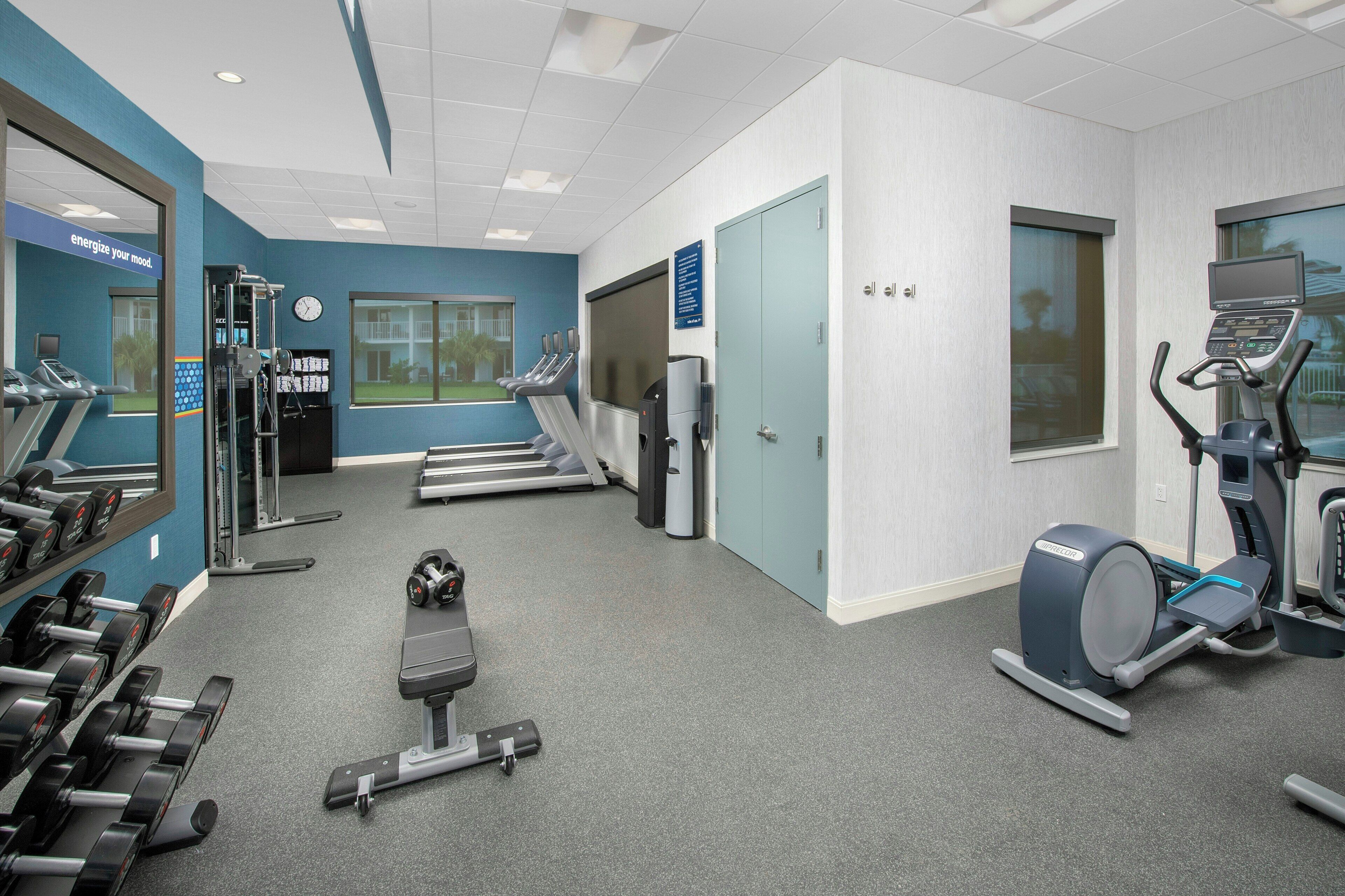 Ein Fitnessstudio mit Laufbändern, Crosstrainern und Gewichten.
