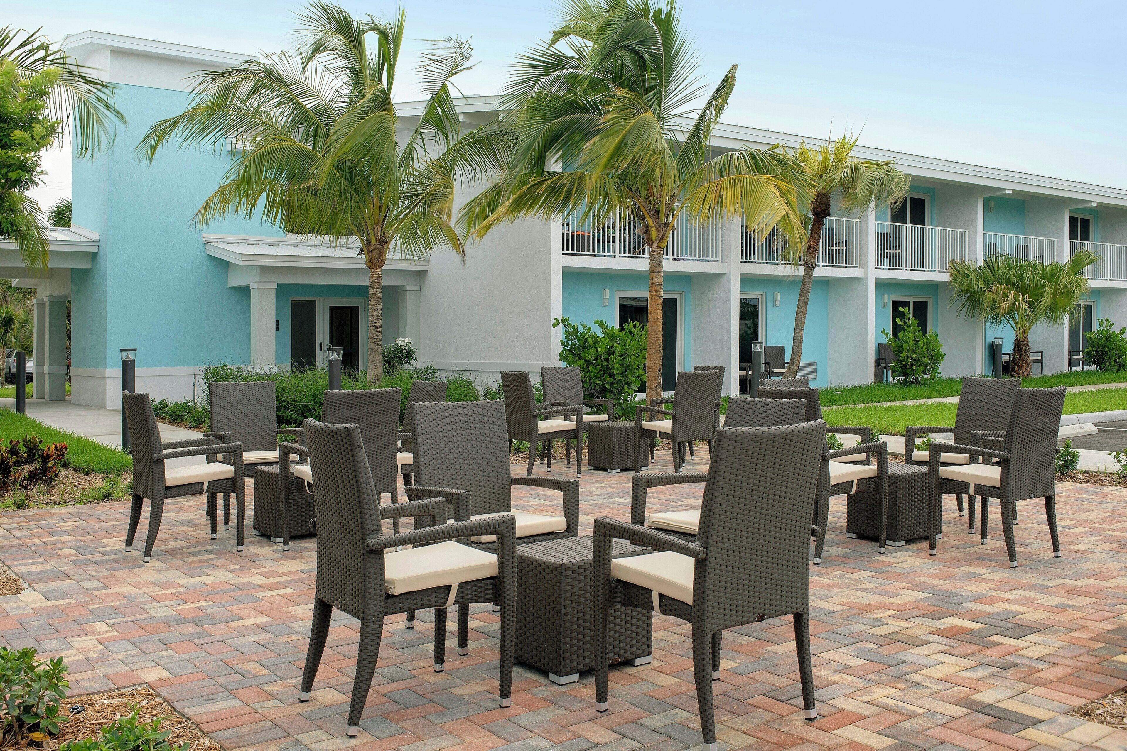 An outdoor patio with wicker furniture and palm trees.