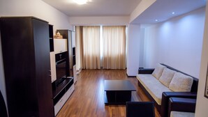 A modern living room with a dark wooden cabinet, a sofa, a coffee table, and a television. - Beach Vibe Apartments  Summerland Mamaia (Constanta)