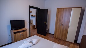 A hotel room with a bed, a TV, wooden wardrobe, and a door leading to a bathroom. - Beach Vibe Apartments  Summerland Mamaia (Constanta)