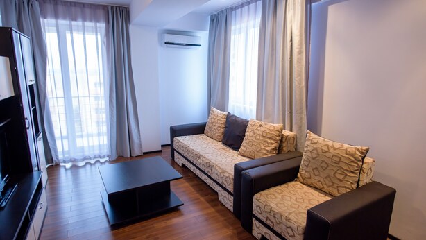 A modern living room with a sofa, a coffee table, and a TV. - Beach Vibe Apartments  Summerland Mamaia (Constanta)