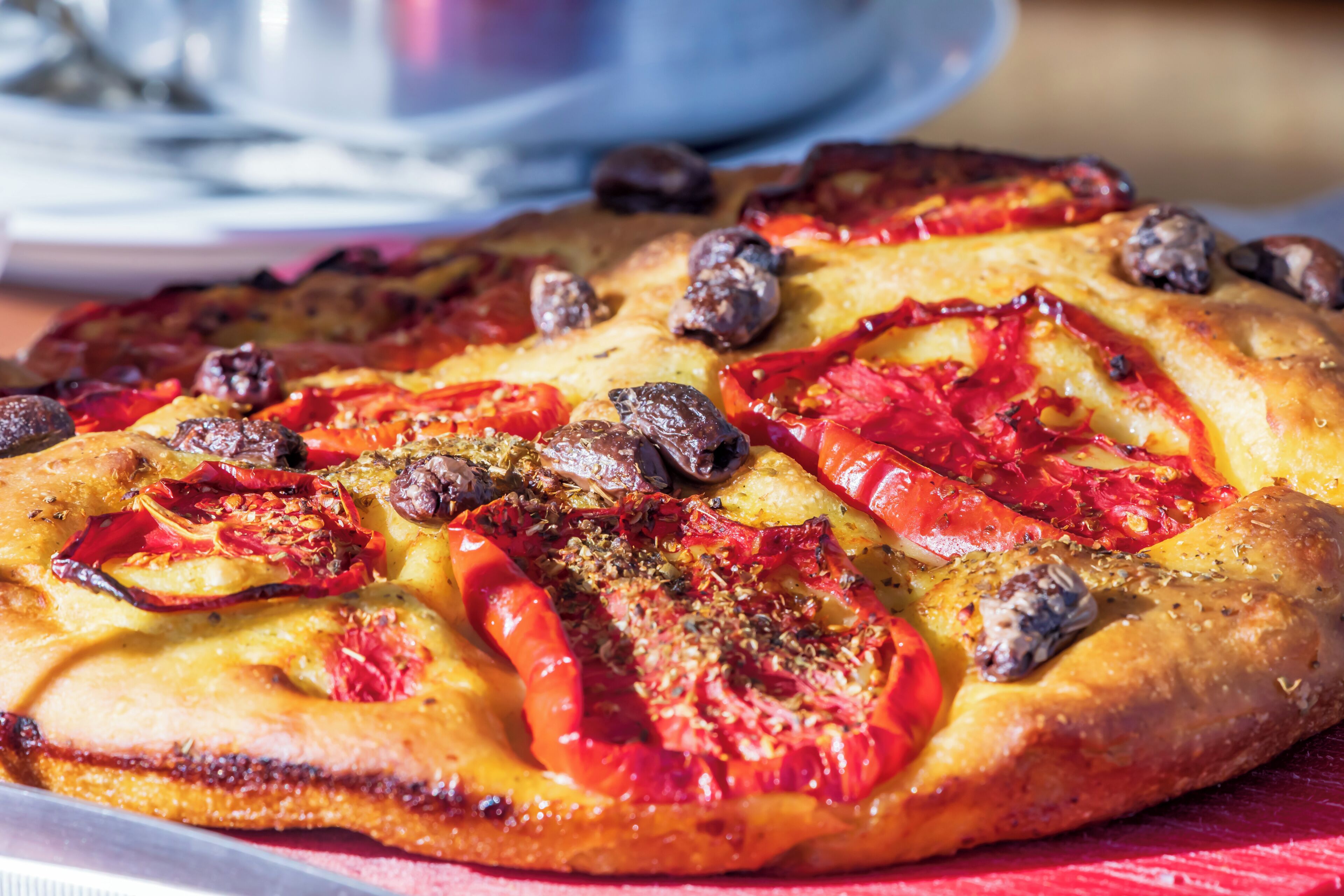 Eine Pizza mit Belag auf einer Holztischplatte.