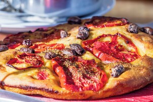 A pizza with toppings on a wooden surface.