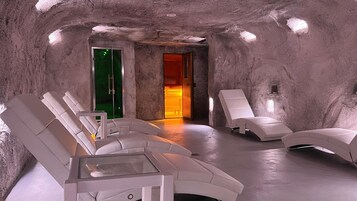 Un cuarto de spa con sillones blancos, una mesa de vidrio y una cálida fuente de luz.