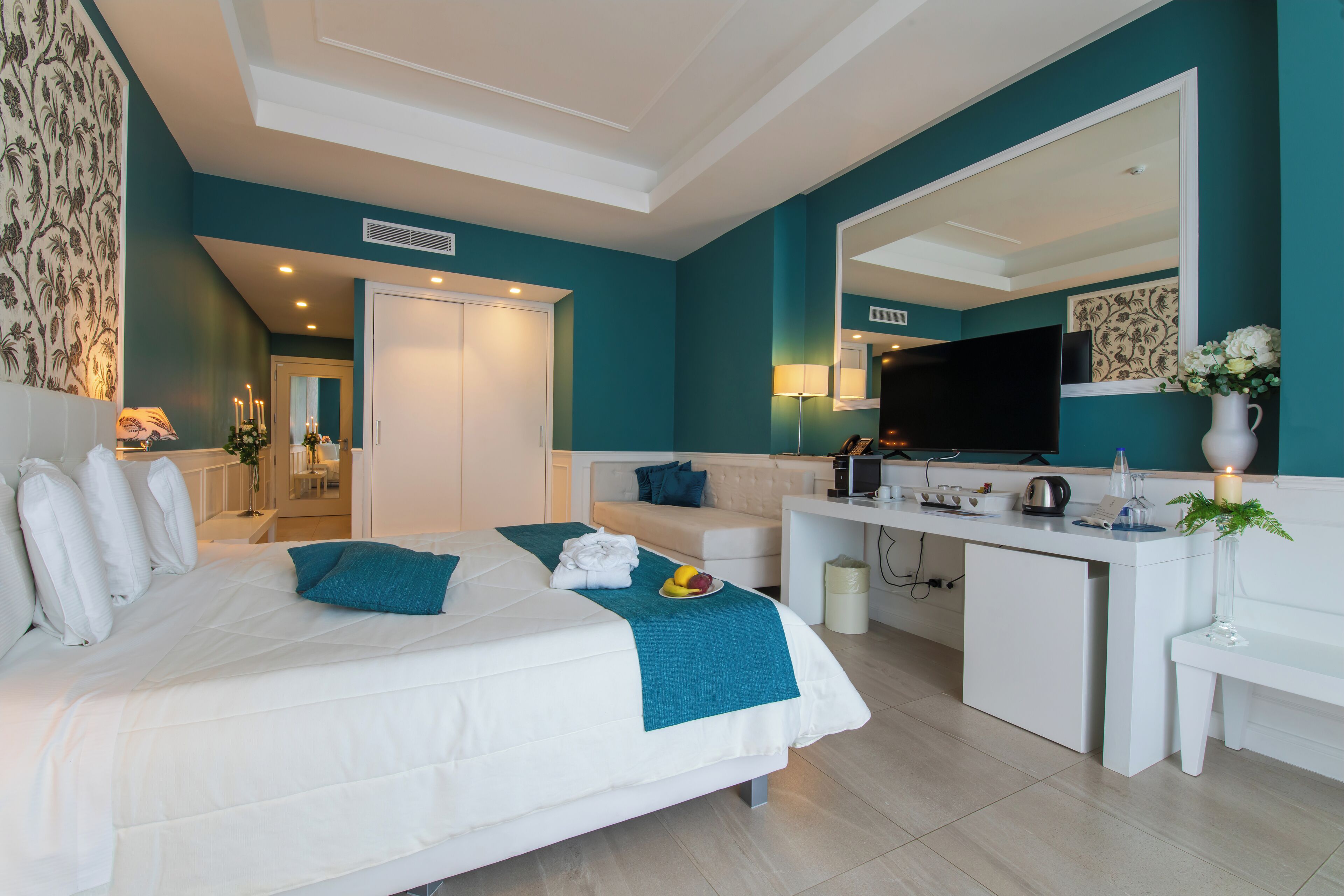Een moderne hotelkamer met een groot bed, een bureau, een televisie en een badkamer op de achtergrond.