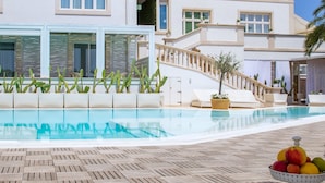 A hotel with a pool, outdoor seating, and a fruit display.