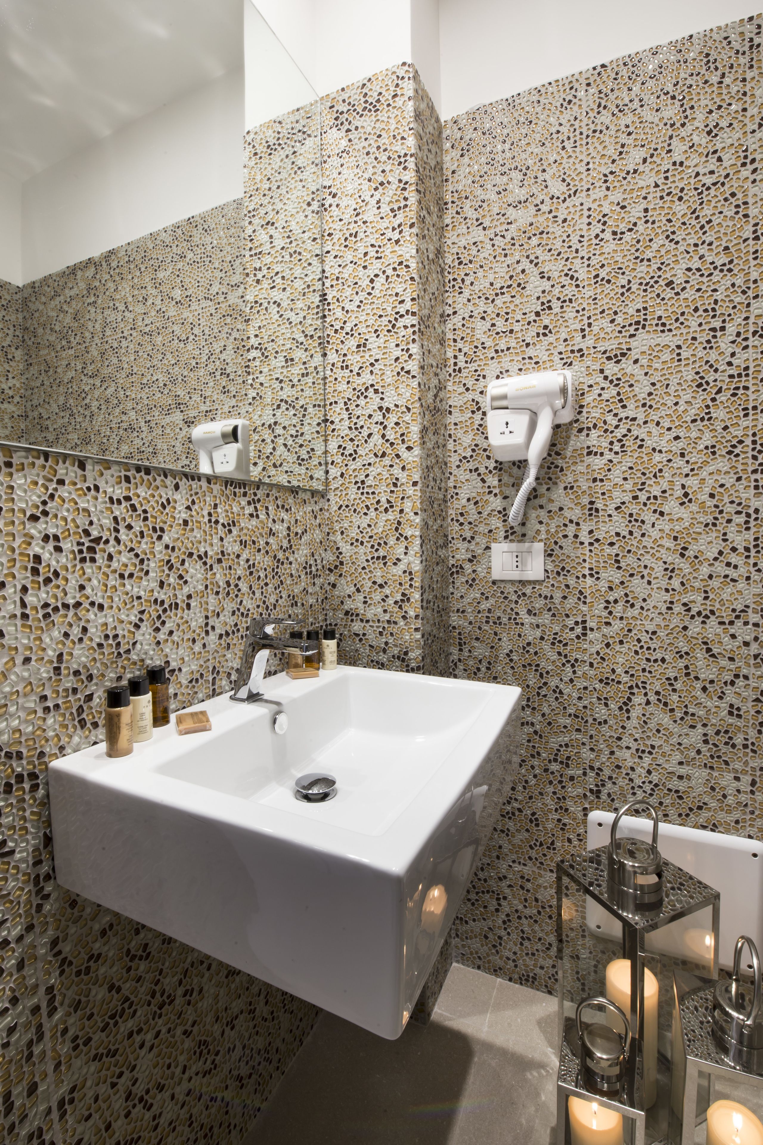 A bathroom with a large white sink, a mirror, and a wall-mounted hairdryer.