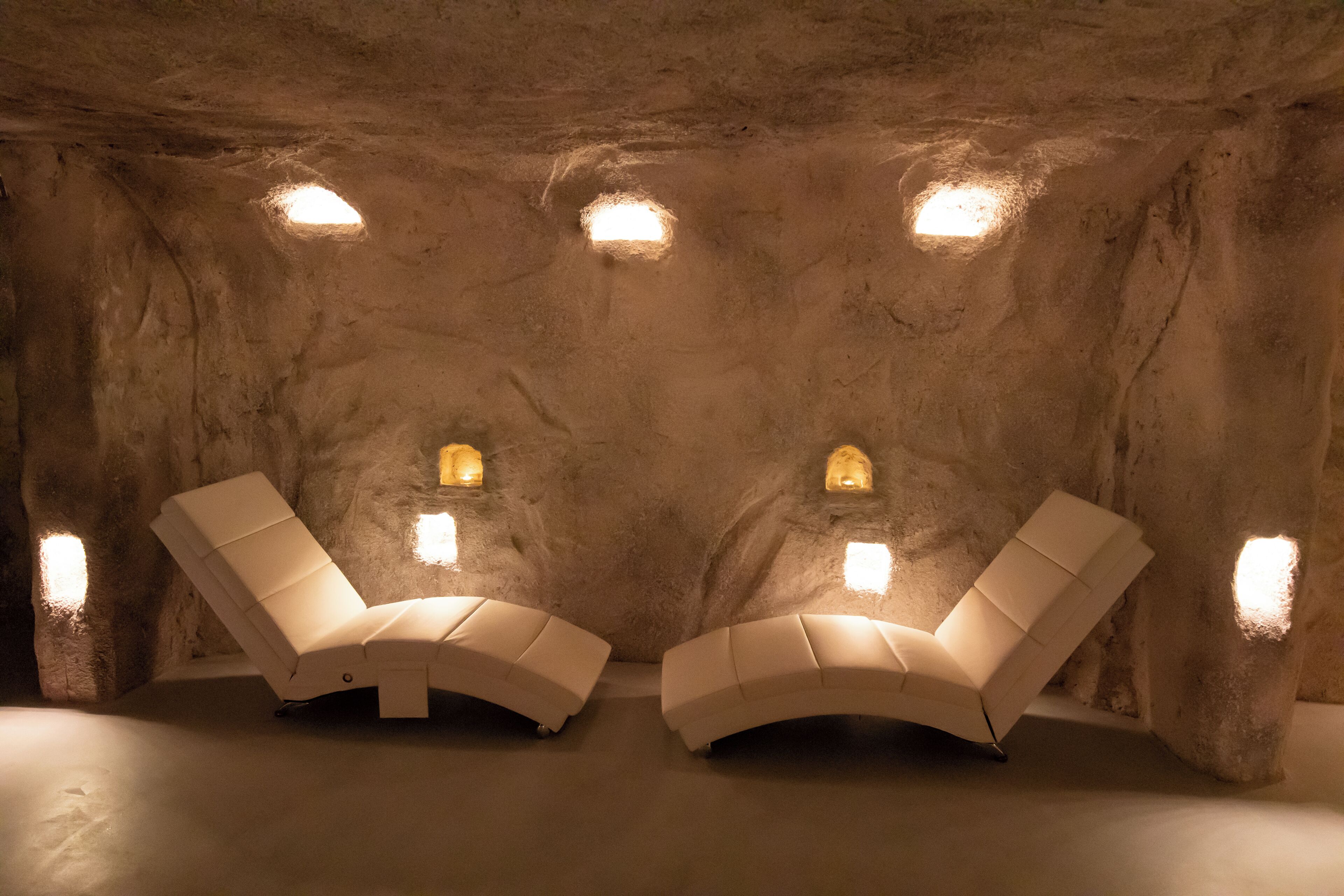 A spa room with two reclining chairs and wall-mounted lights.