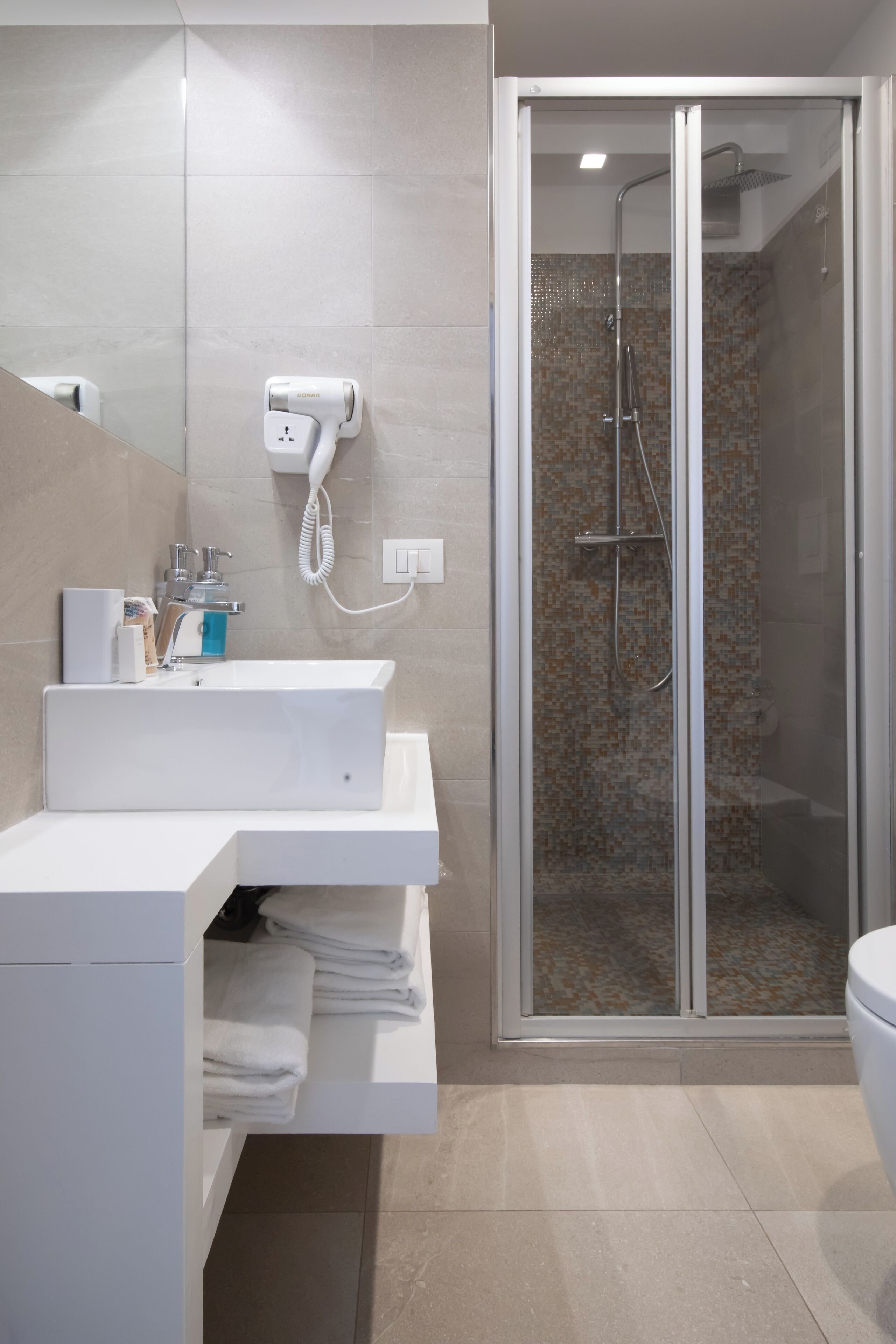 A modern bathroom with a glass-enclosed shower, a white sink, and a mirror.