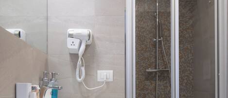 A modern bathroom with a glass-enclosed shower, a white sink, and a mirror.