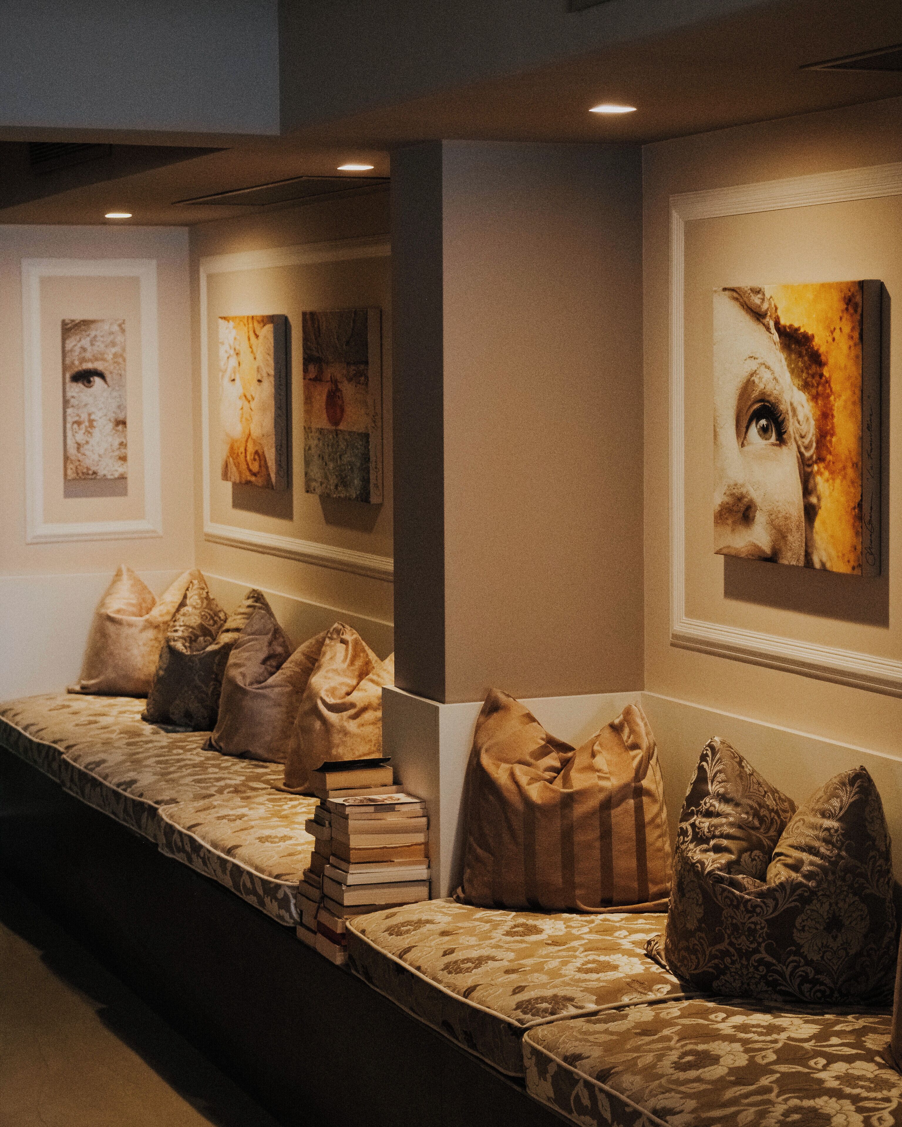 A hallway with a bench, pillows, and framed artwork on the walls.