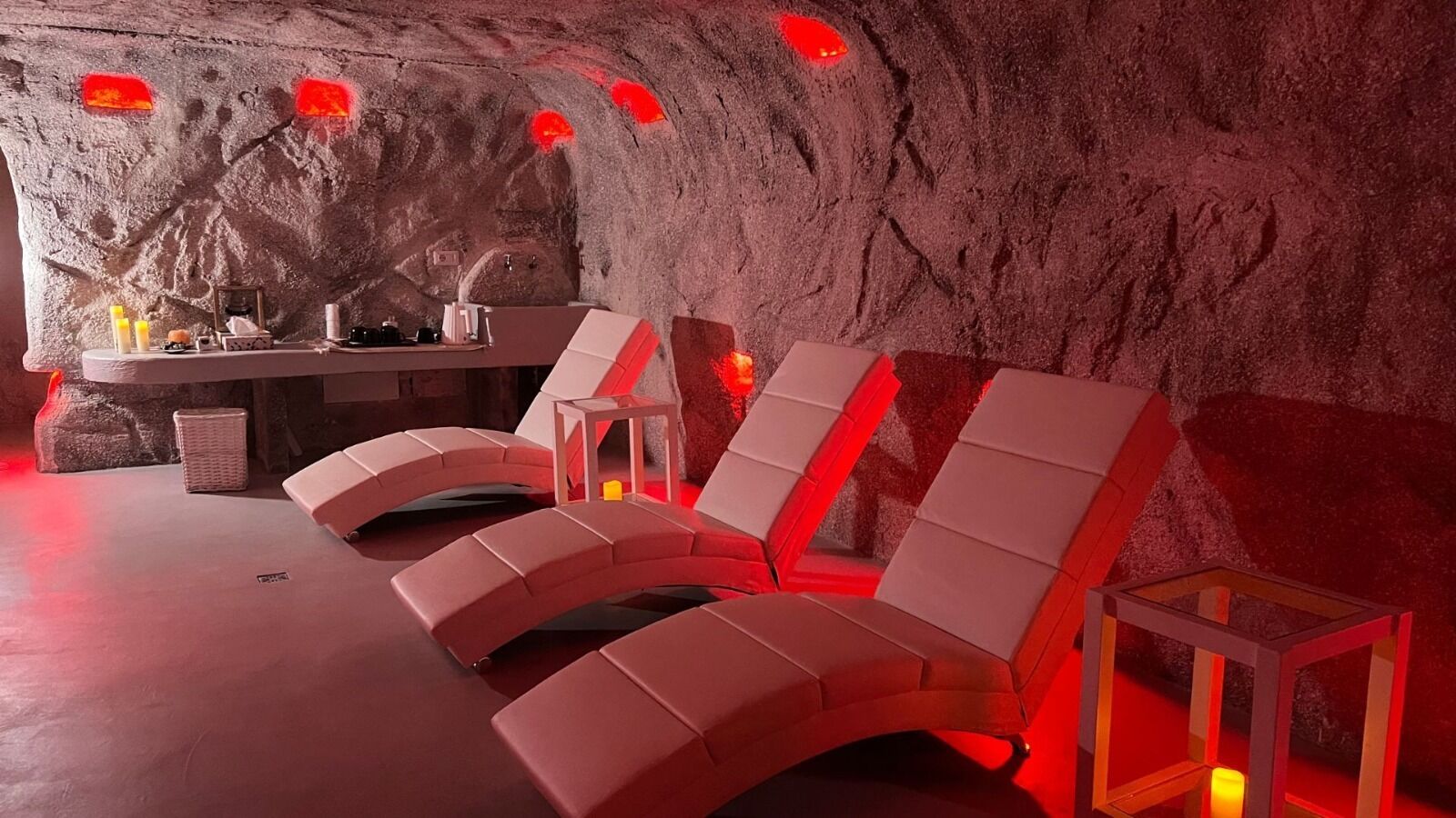 Zona de spa con asientos iluminados en rojo y un fondo de pared de piedra.