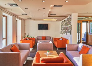 A modern lobby with sofas, a flat-screen TV, and a wall of photos.
