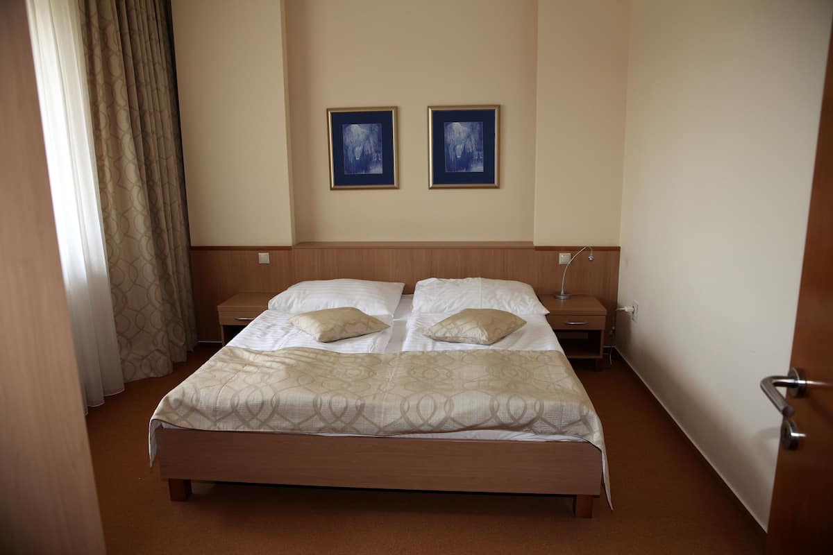 Habitación de hotel con una cama grande, dos mesitas de noche y dos cuadros en la pared.