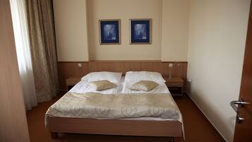 Habitación de hotel con una cama grande, dos mesitas de noche y dos cuadros en la pared.