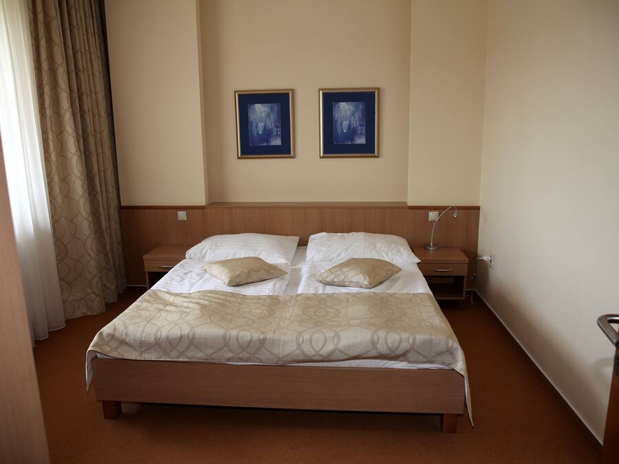 Habitación de hotel con una cama grande, dos mesitas de noche y dos cuadros en la pared.