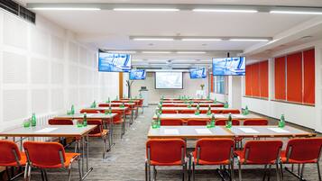 A conference room with multiple tables and chairs, equipped with projectors and screens.