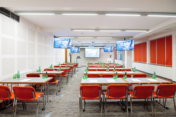 A conference room with multiple tables and chairs, equipped with projectors and screens.