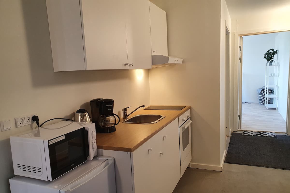 A compact kitchen with white cabinets, a microwave, a coffee maker, and a sink.