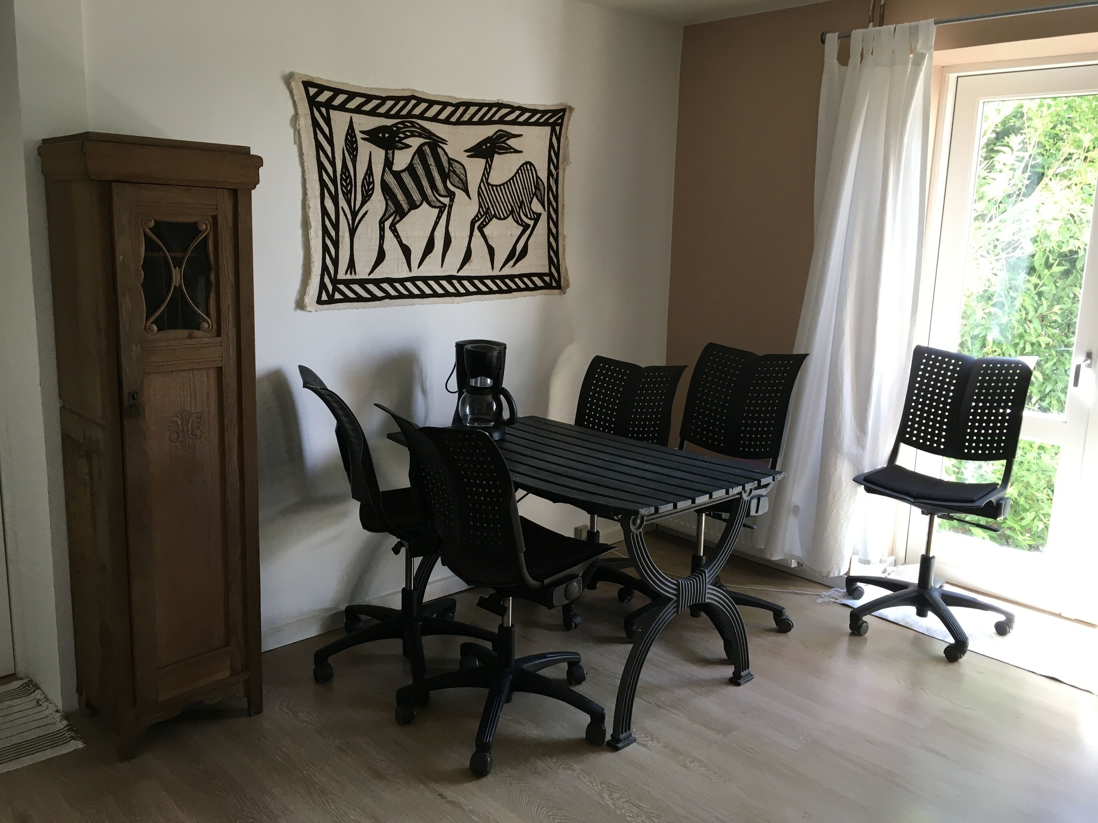 A dining area with a wooden cabinet, a table with four chairs, and a wall-mounted artwork of animals.